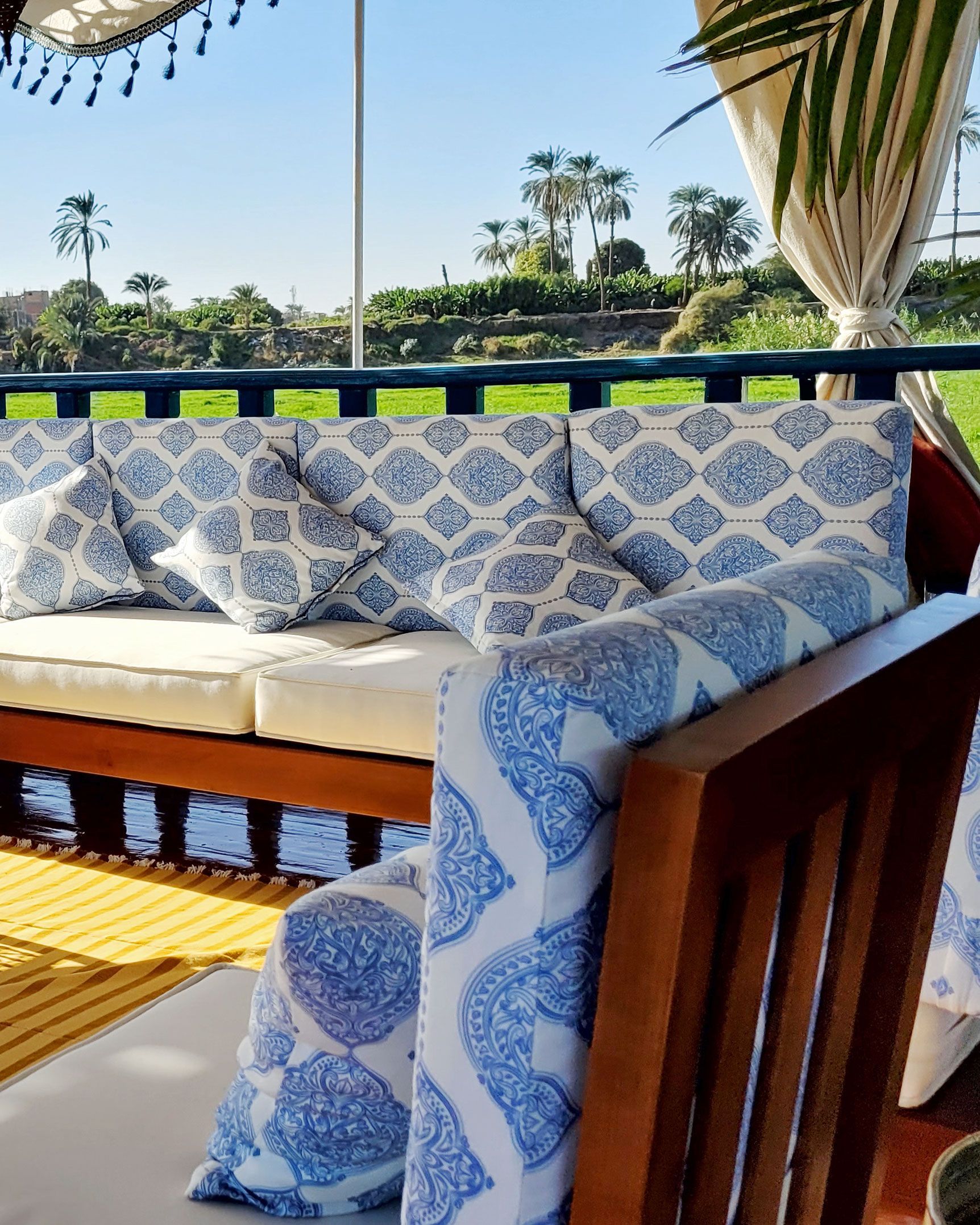 A photo of a cozy seating area on the deck of a traditional Egyptian sailing boat, the Dahabiya Kingfisher, which offers private cruises along the Nile river between Luxor and Aswan.