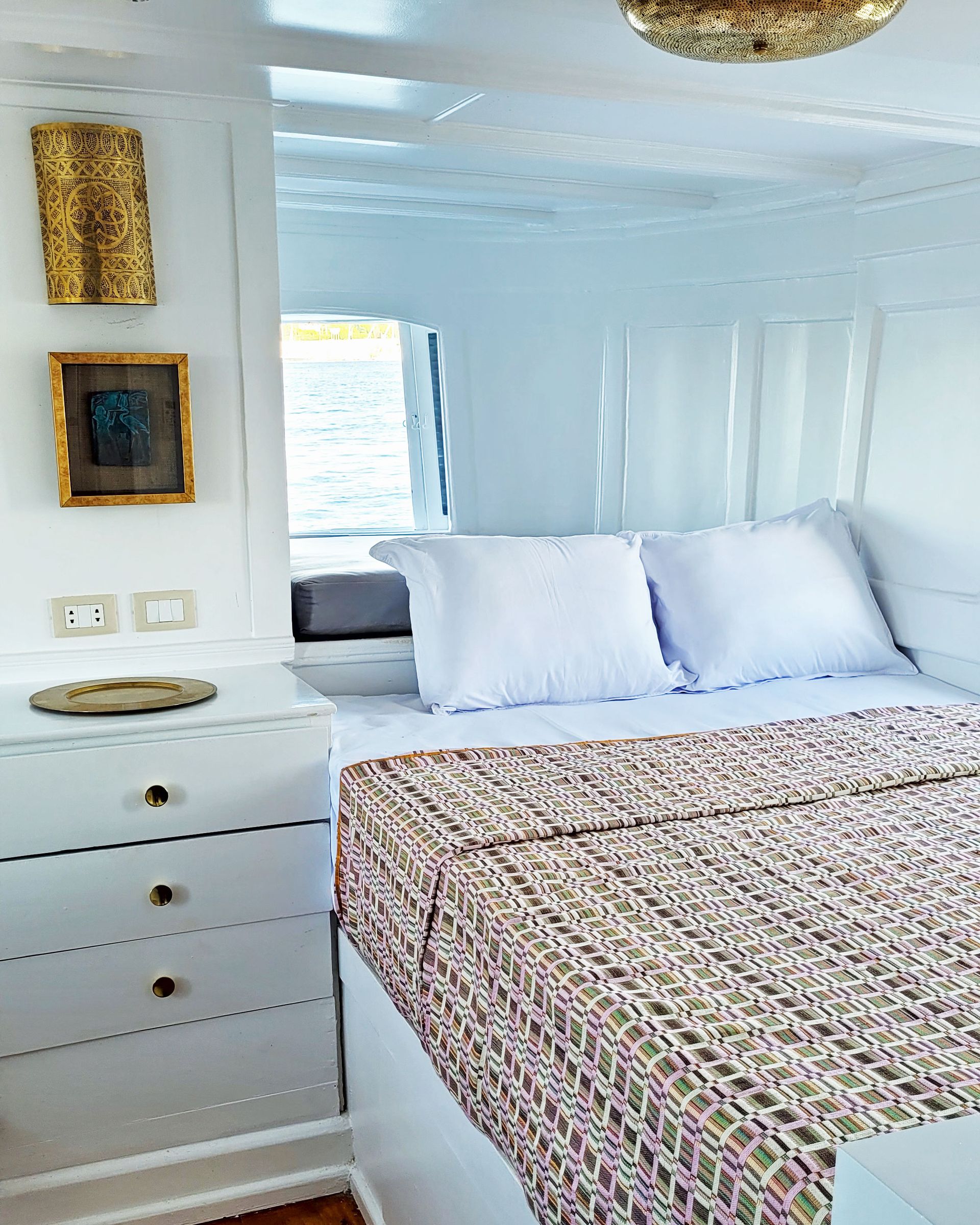 A picture of a cozy and elegant cabin/suite on the Dahabiya Kingfisher, a historic boat that offers exclusive Nile cruises between Luxor and Aswan. The Dahabiya Kingfisher is the original 1899 boat that was used by aristocrats and royalty to explore the Nile in style and comfort.