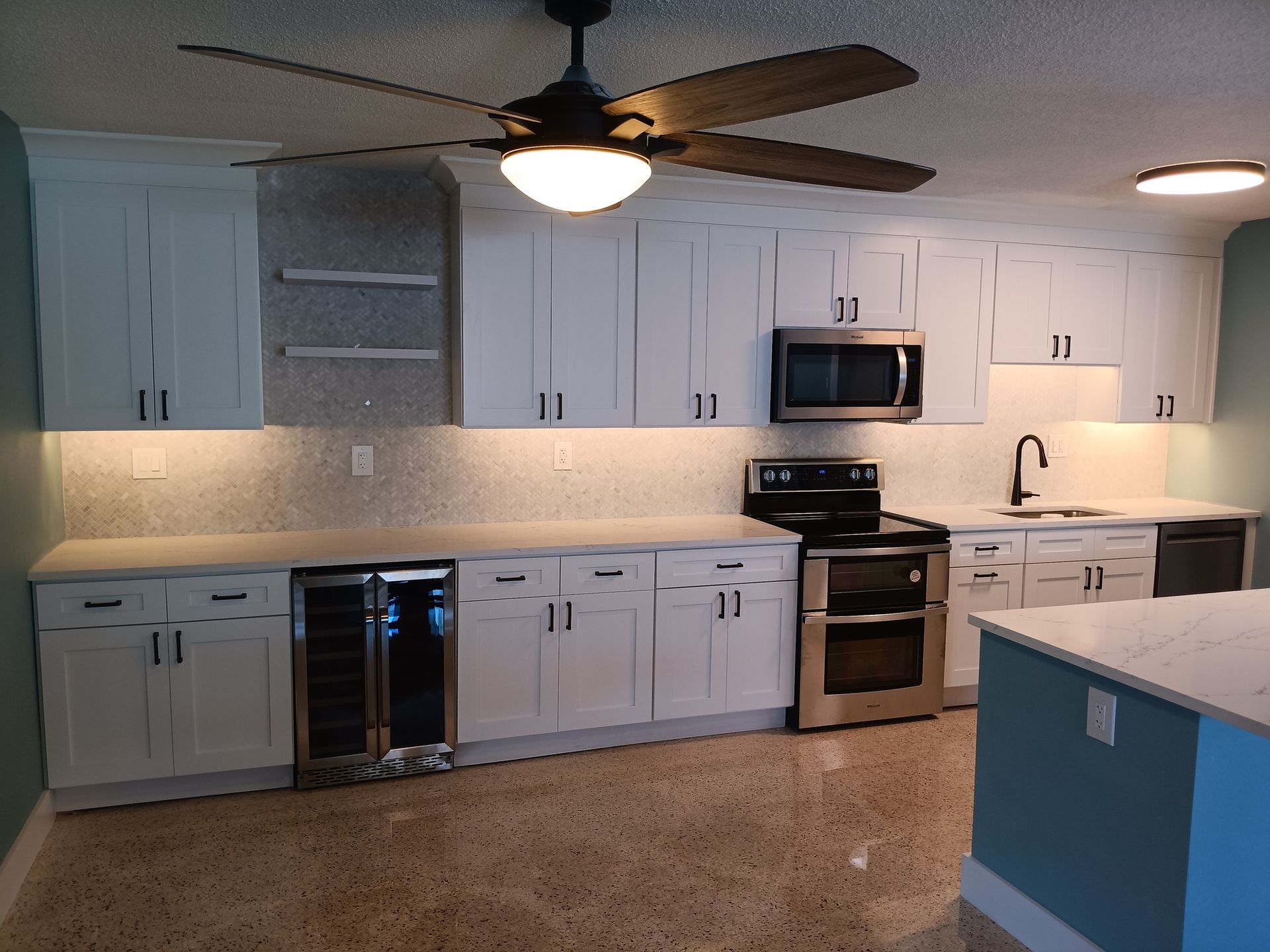 Modern kitchen with white cabinets, stainless steel appliances, and a polished concrete floor.