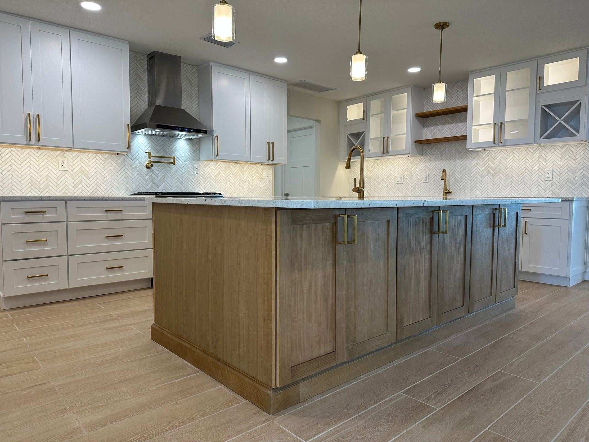 Modern kitchen with white and wood cabinets, gold hardware, and a large central island.