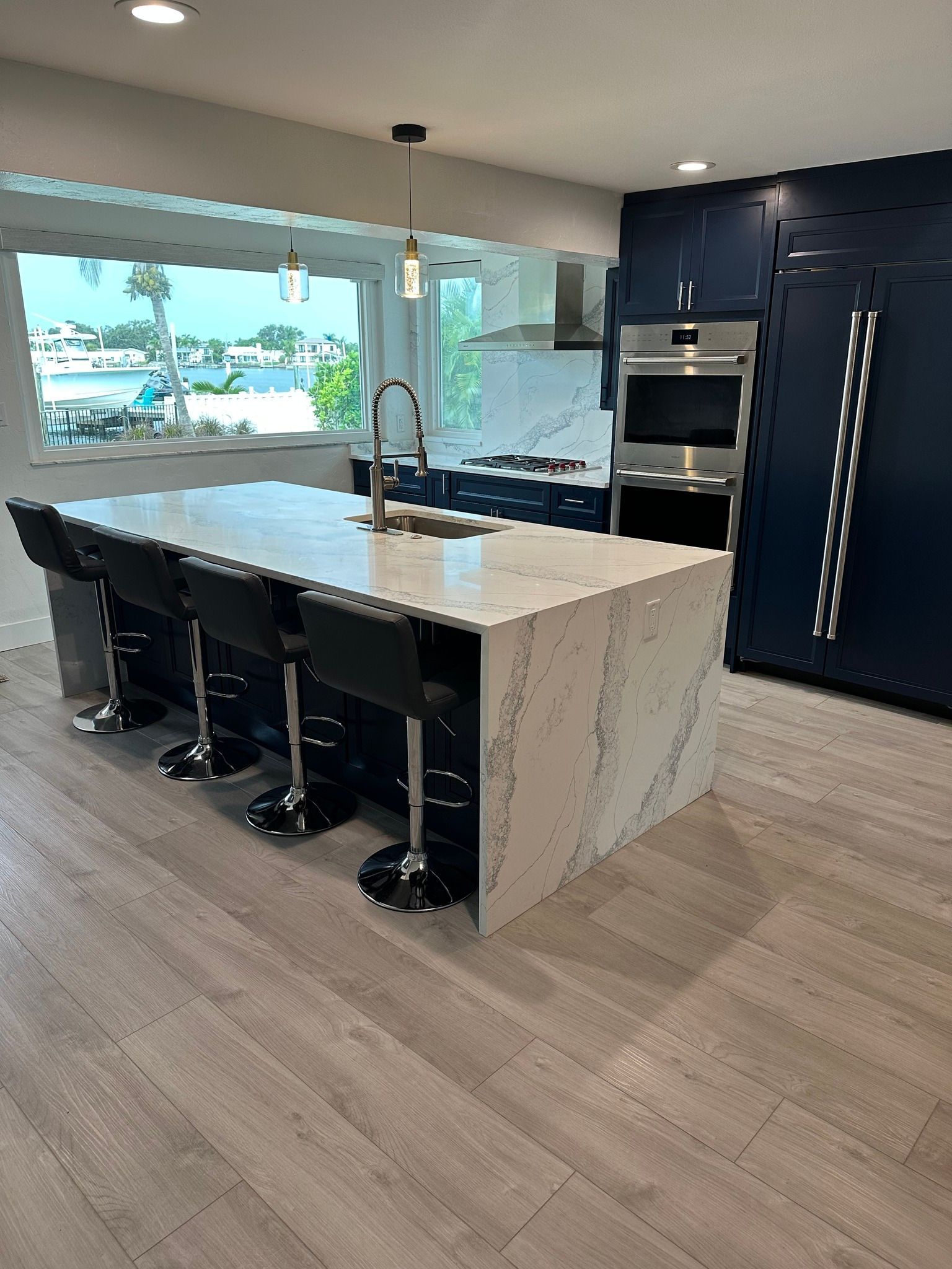 Modern kitchen with navy blue cabinets, white countertops, and an island with bar stools.