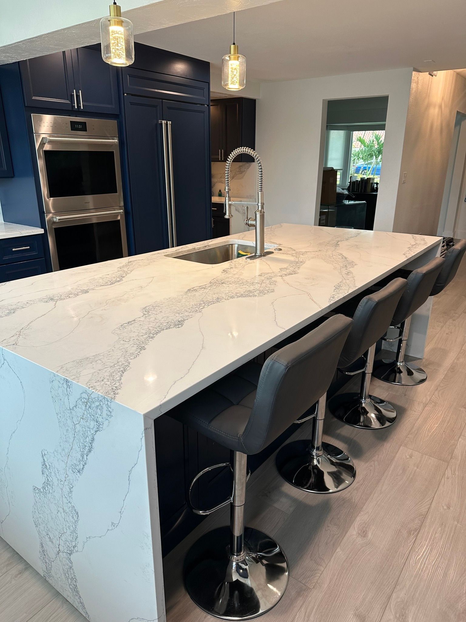 Modern kitchen with blue cabinets, a white island, and gray bar stools.