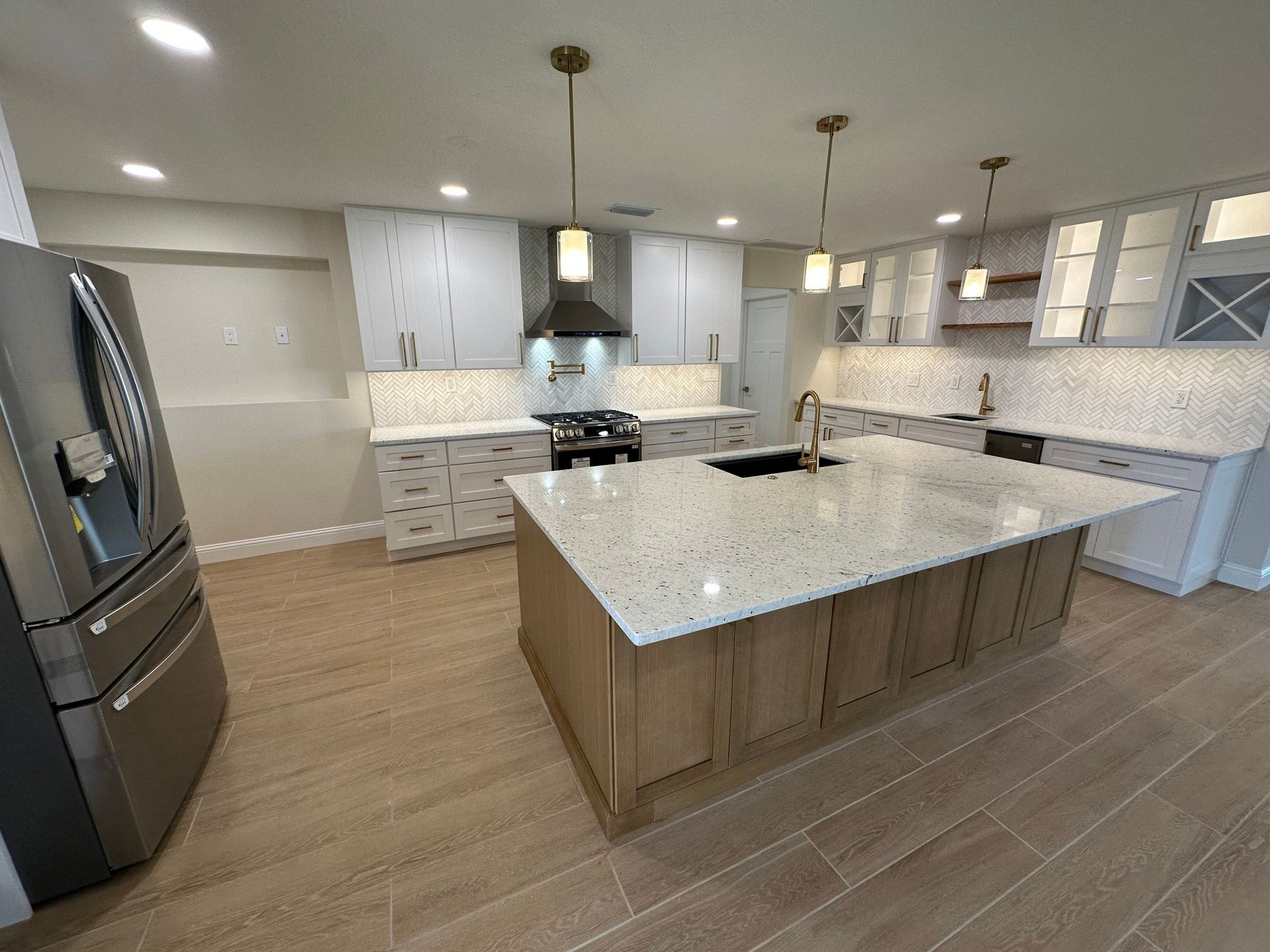 Modern kitchen with light wood cabinets, quartz countertops, and a large island.