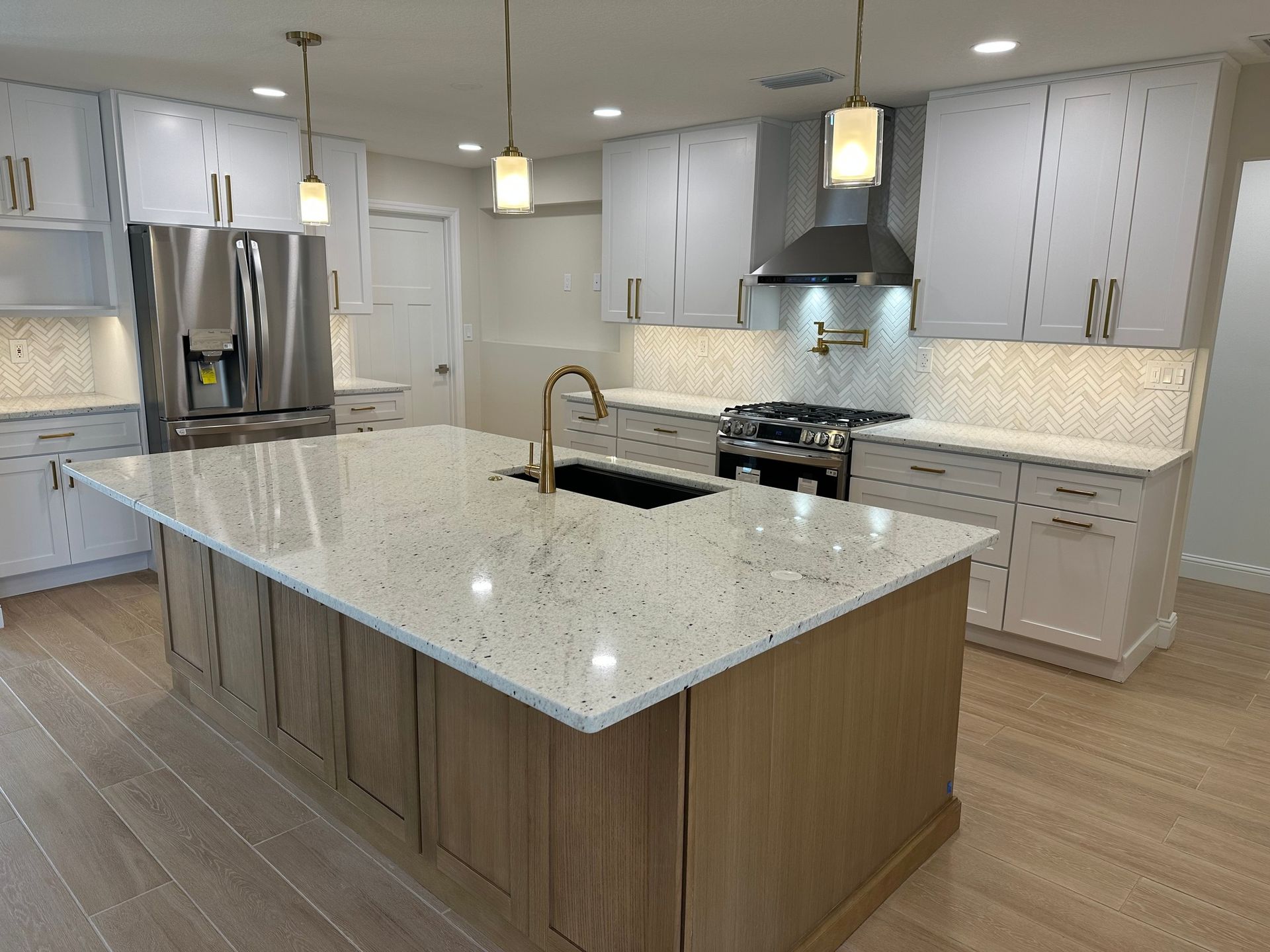 Modern kitchen with white cabinets, wood island, and stainless steel appliances.