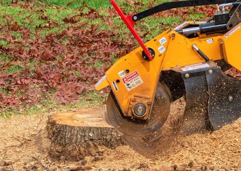 Stump Grinder is Cutting a Tree Stump in the Grass — Baton Rouge, LA — Capital City Tree Care LLC