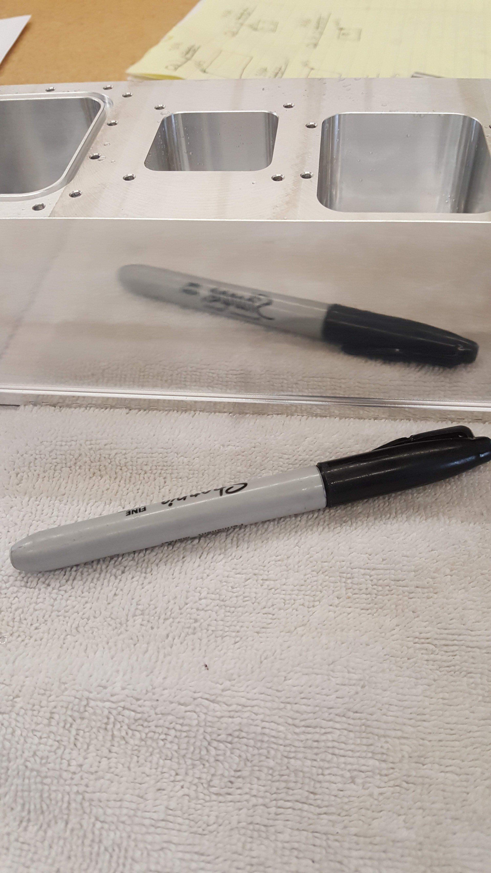 A sharpie marker is sitting on a piece of metal.