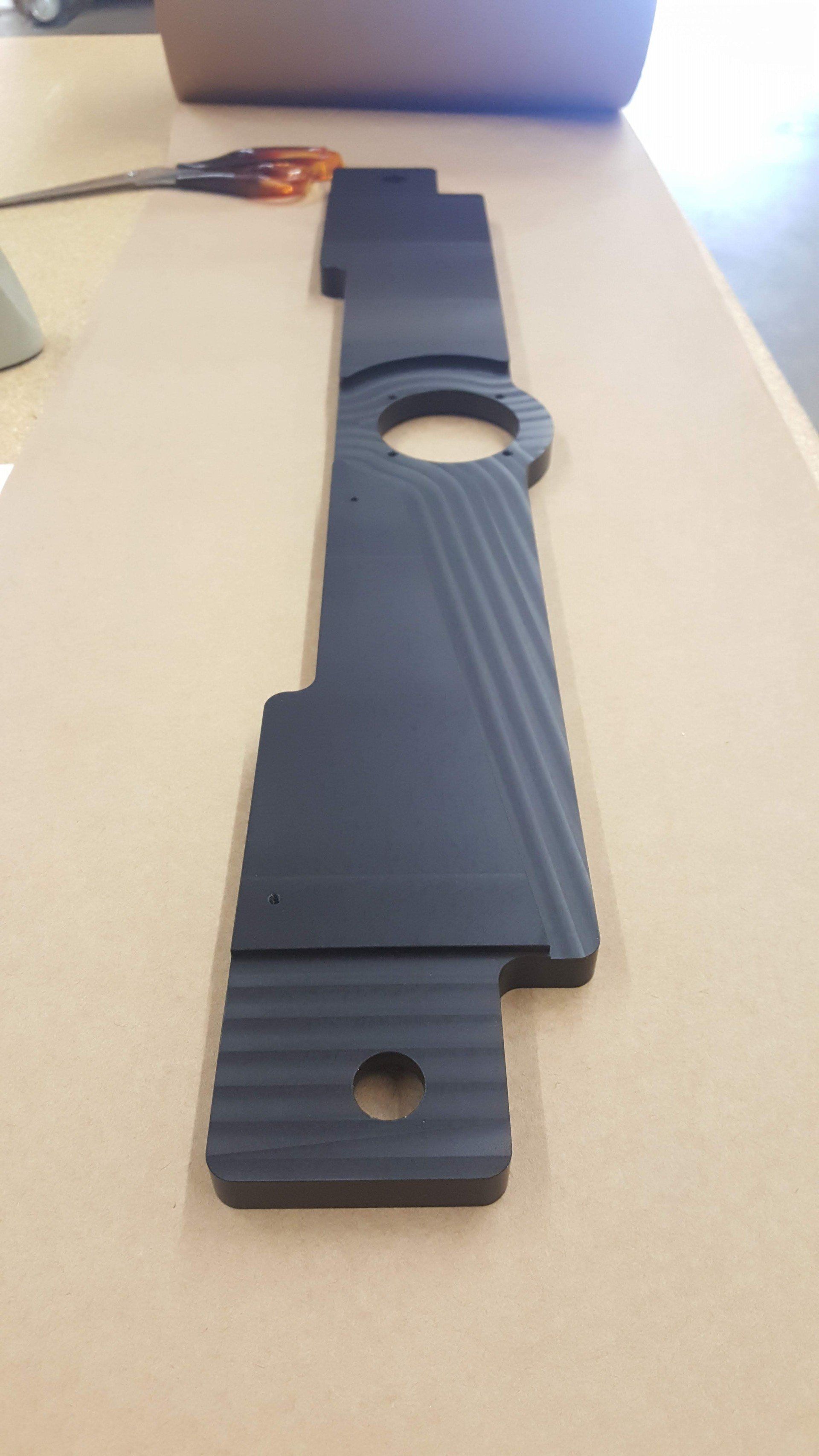 A black piece of metal is sitting on top of a wooden table.