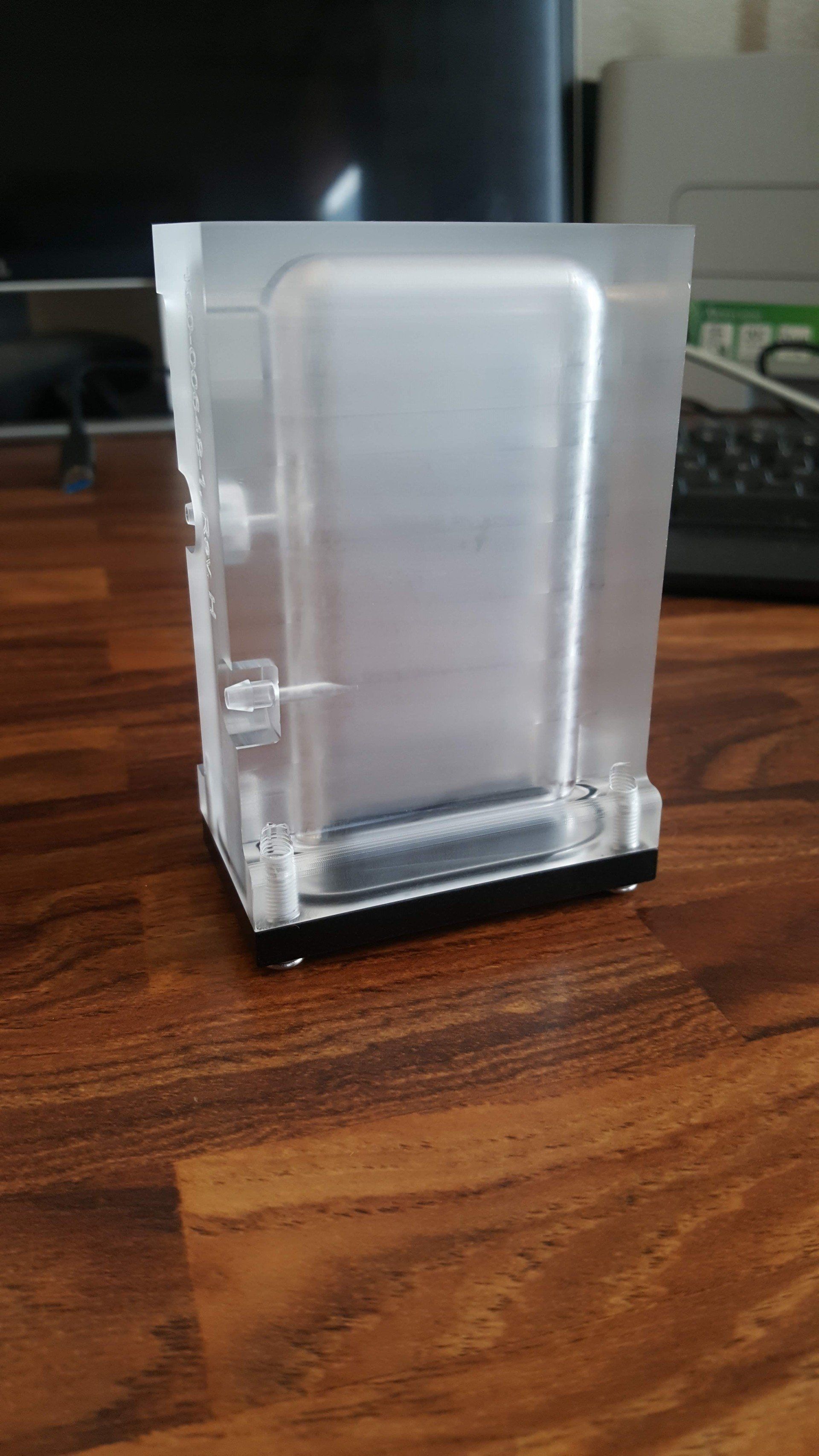 A cell phone in a clear plastic case is sitting on a wooden table.