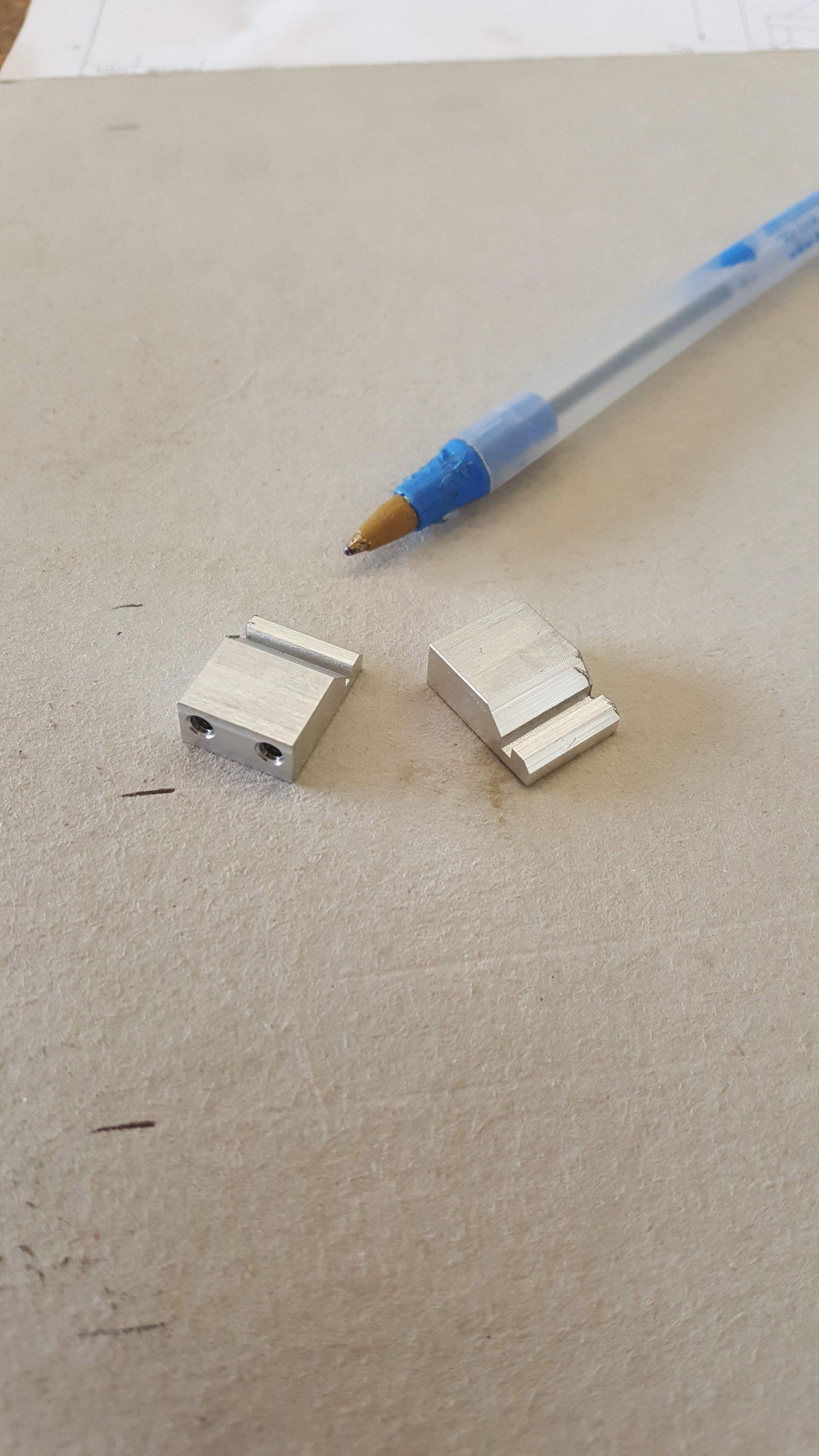 A pen is sitting next to a piece of metal on a piece of paper.