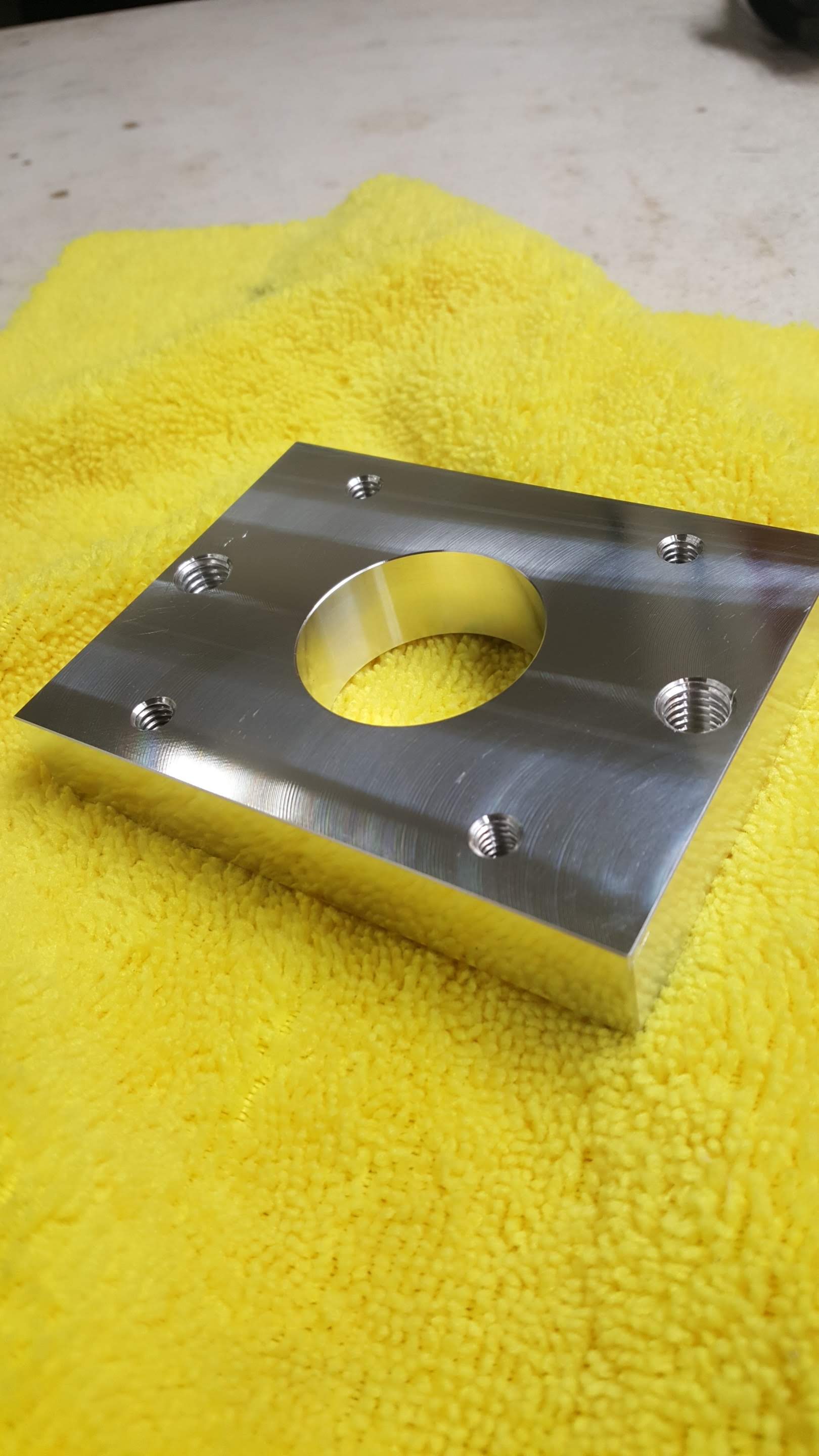 A piece of metal with a hole in the middle is sitting on a yellow towel.