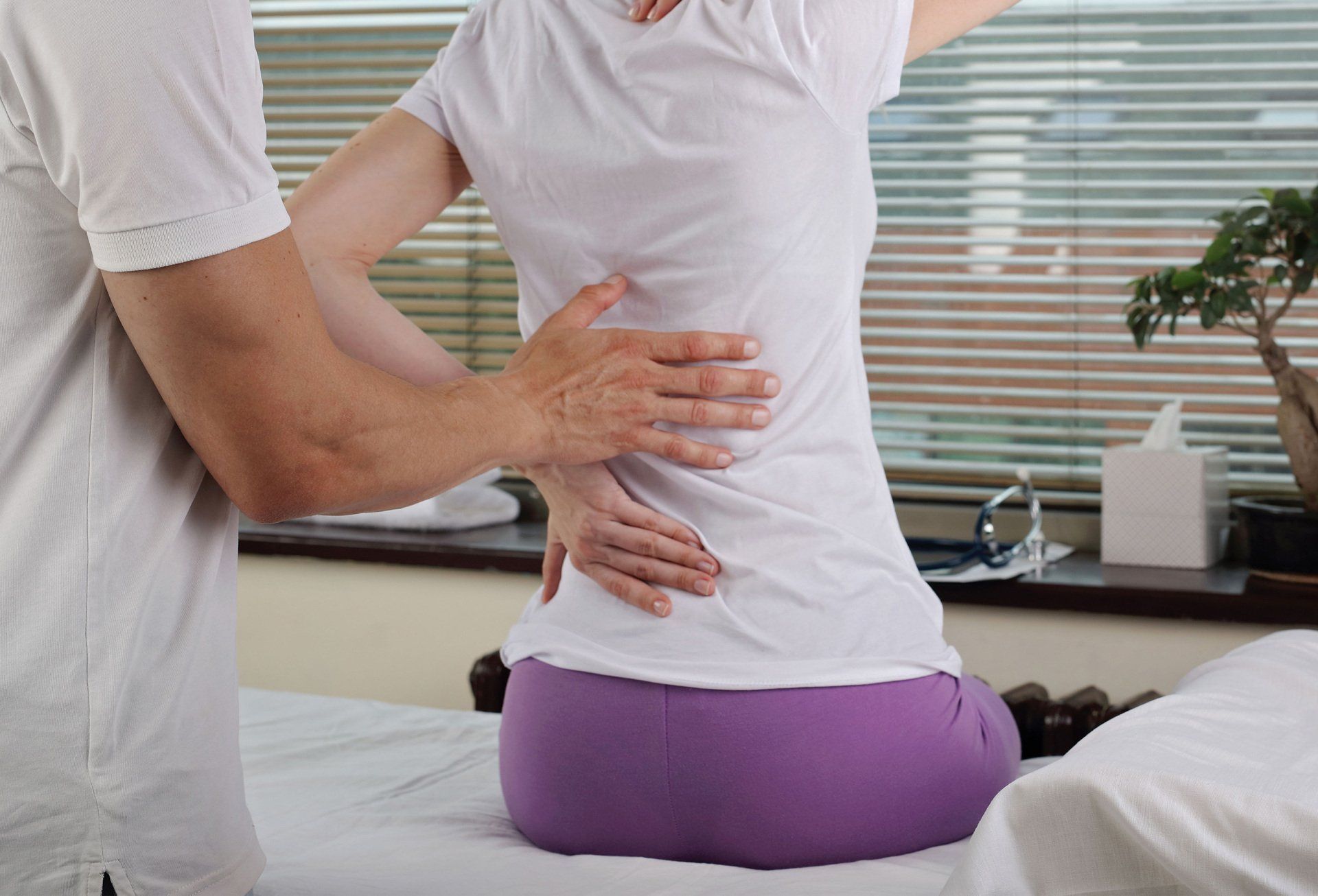 A woman is sitting on a bed getting a massage from a man.