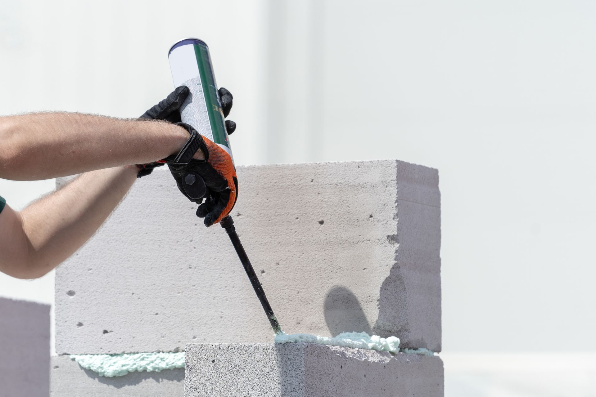 A man is applying foam to a concrete block.