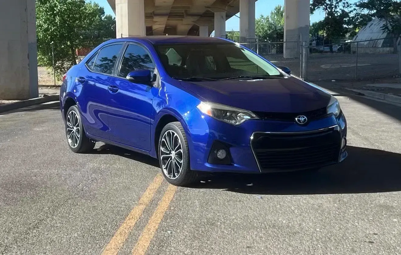 Blue Toyota Corolla parked on asphalt under a concrete overpass, sunny day | Nonstop Auto Reno, NV