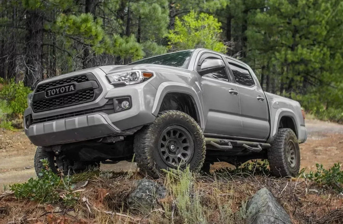 Silver Toyota Tacoma truck off-roading on a dirt trail in a forest | Nonstop Auto Reno, NV
