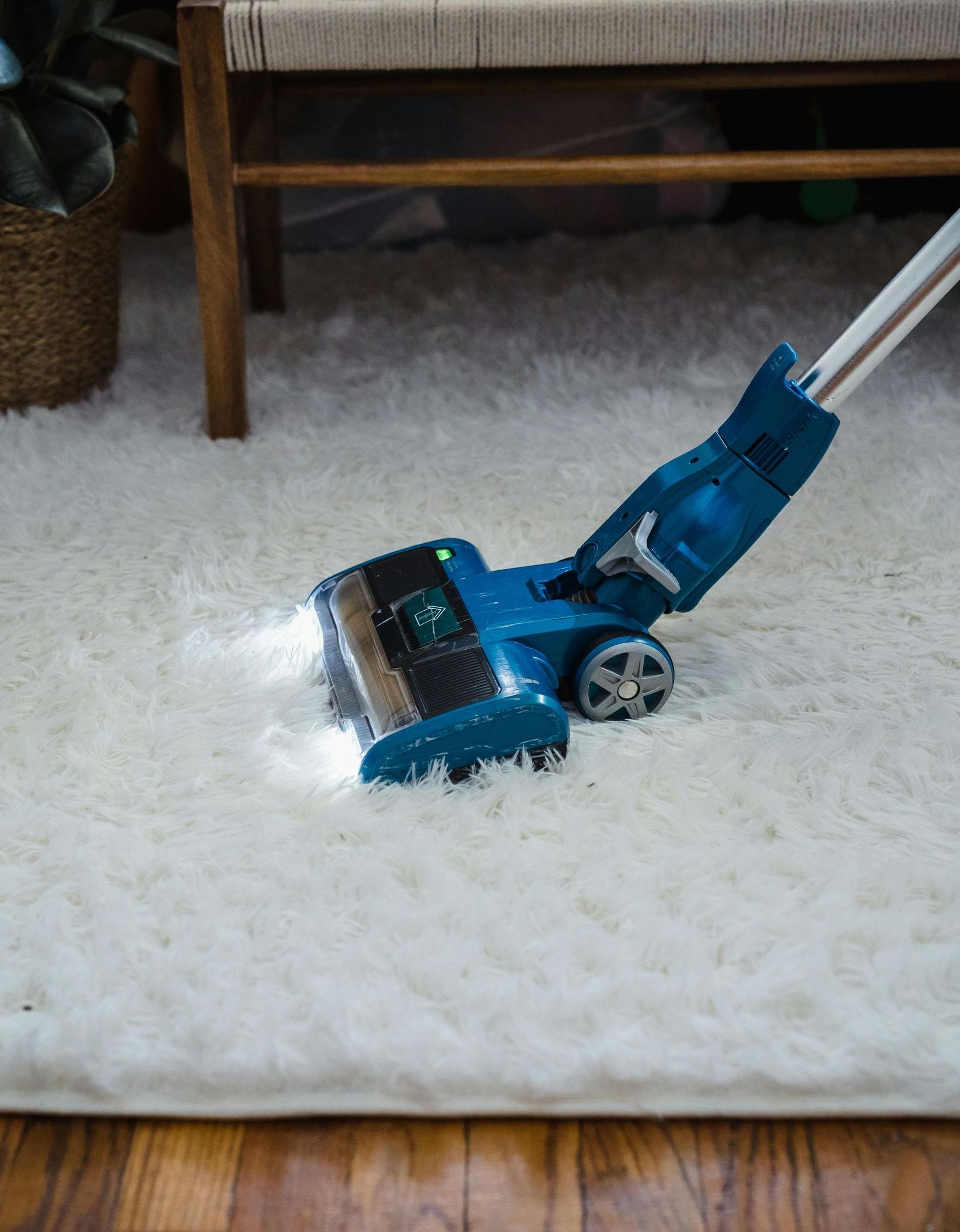 A man in a protective suit is cleaning a rug with a vacuum cleaner.
