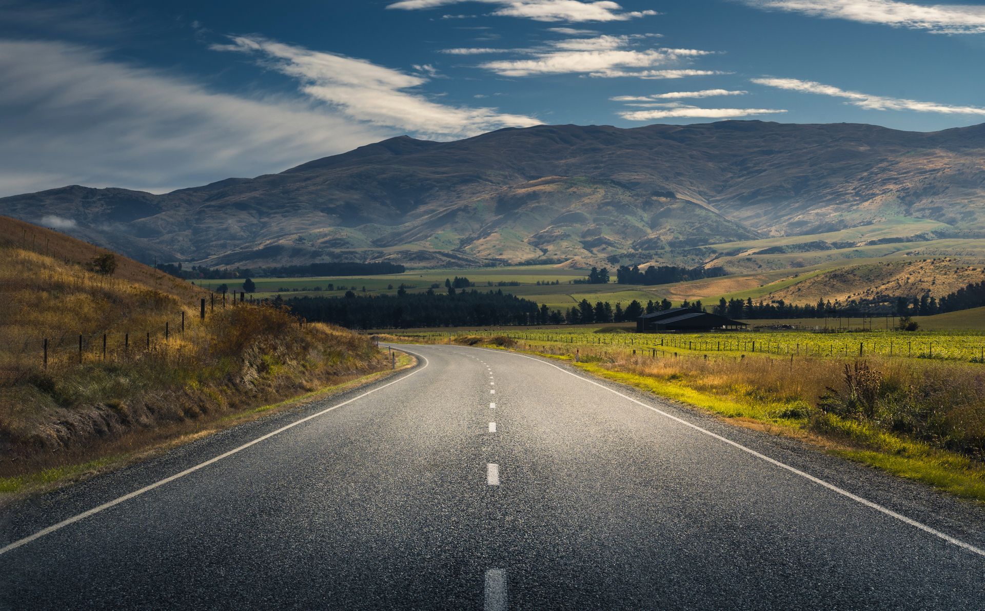 A road going through a valley with mountains in the background.