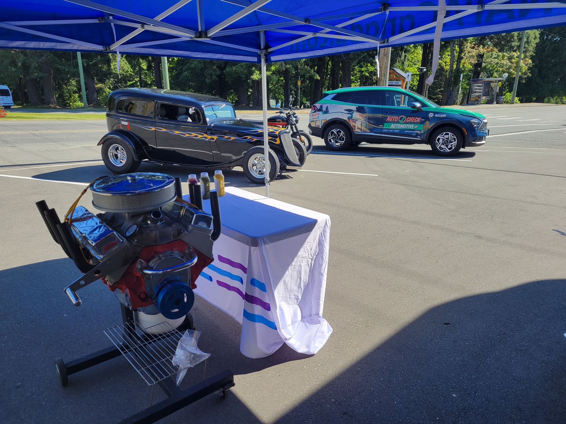 A car engine is sitting on a table in front of a blue tent. | Auto Check Automotive Ltd.