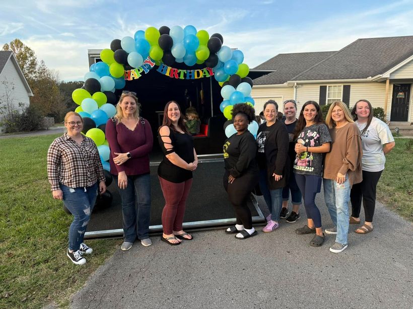 A group of women are standing in front of a trailer decorated with balloons.