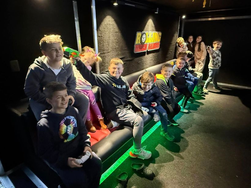 A group of children are sitting on a couch playing a video game.