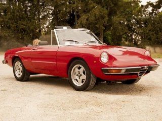 Una decappottabile rossa è parcheggiata su una strada sterrata.