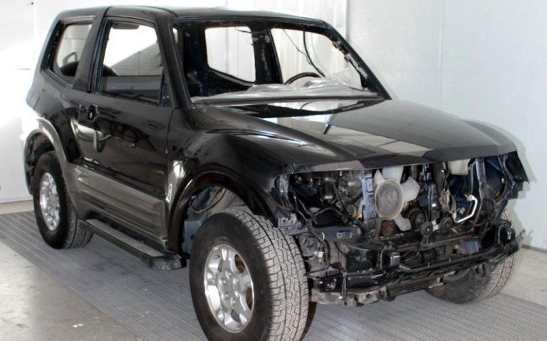 Un'auto nera con il cofano smontato è parcheggiata in un garage.