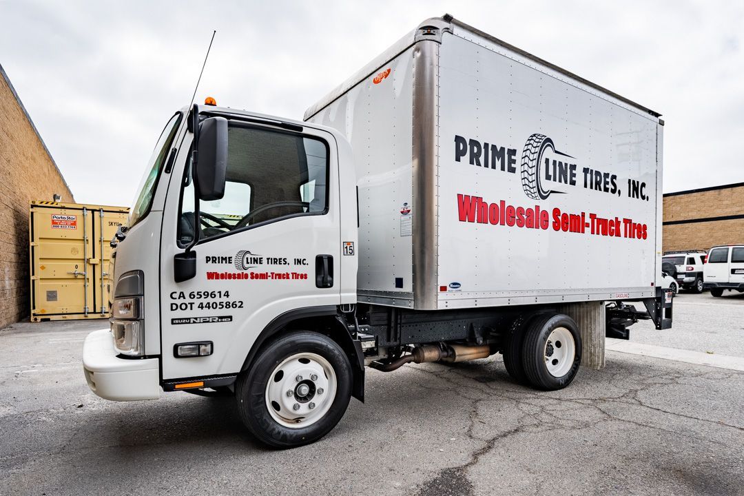 White box truck for Prime Line Tires, Inc. parked outside a building.