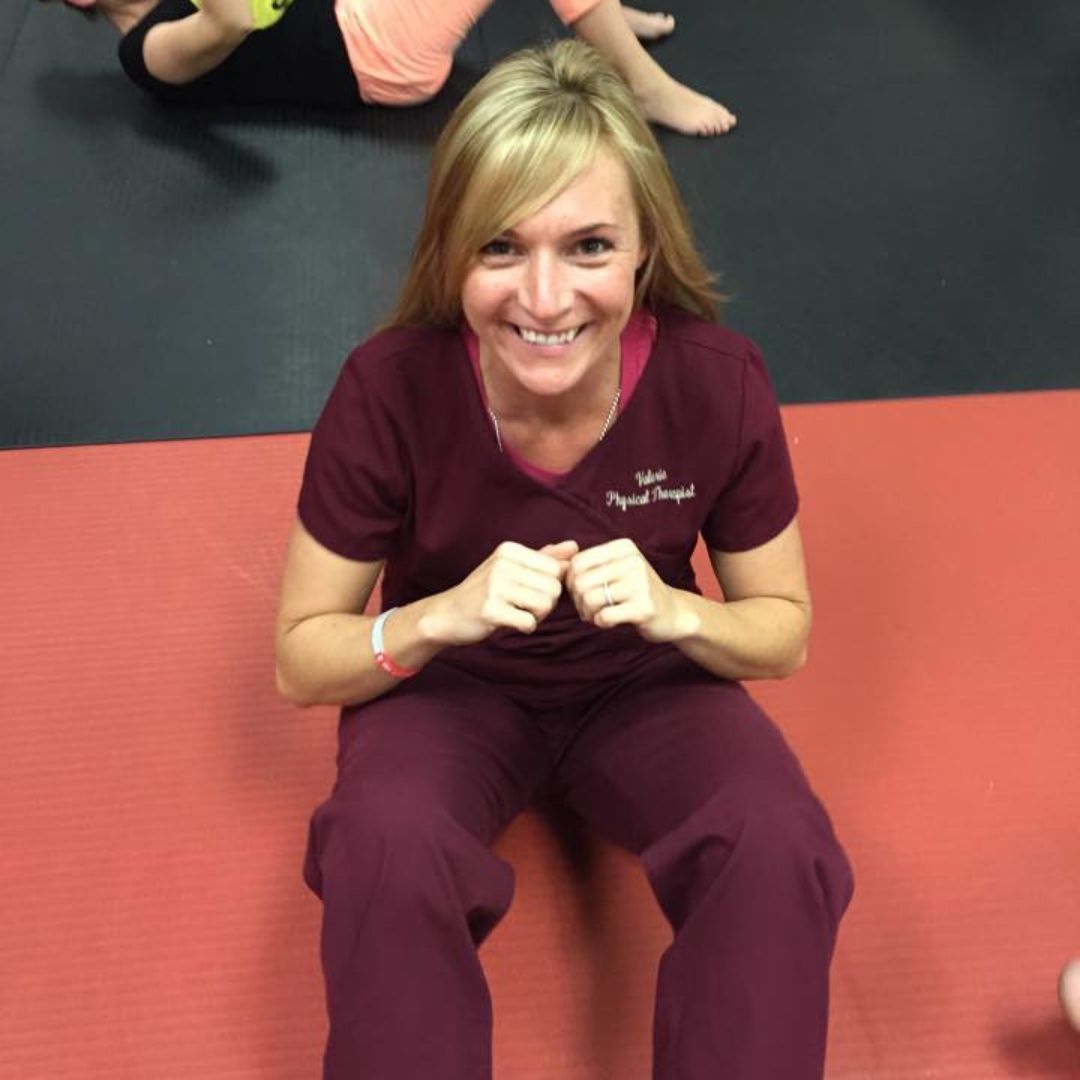 A woman is wearing pink boxing gloves in a gym.
