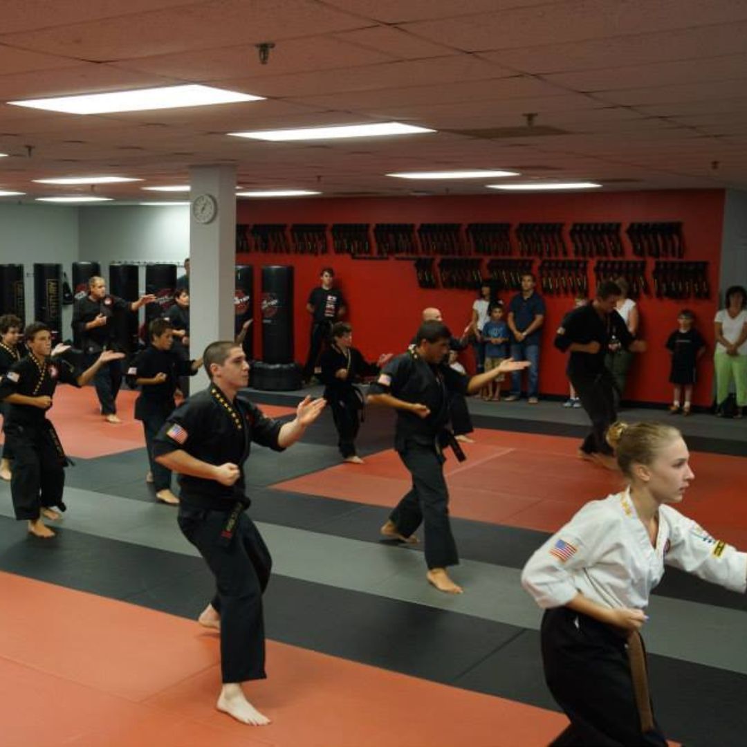 A group of men are practicing karate in a gym.