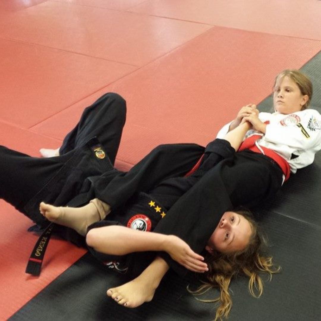 Two young men are practicing karate on a mat