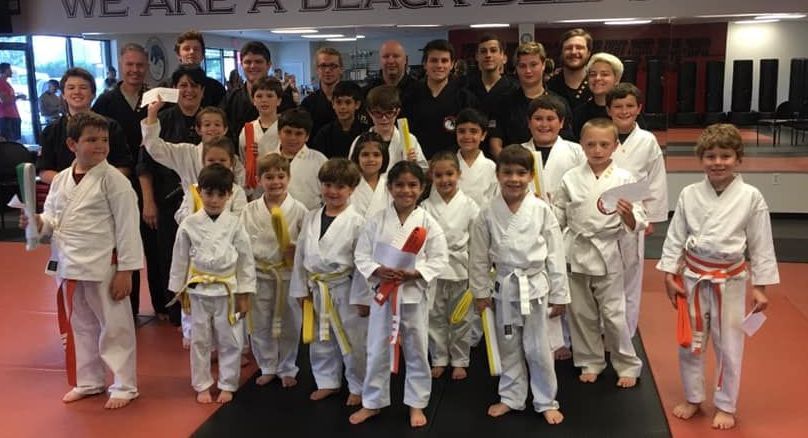 A group of young children in karate uniforms are posing for a picture.