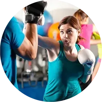 A woman is boxing with a man in a gym