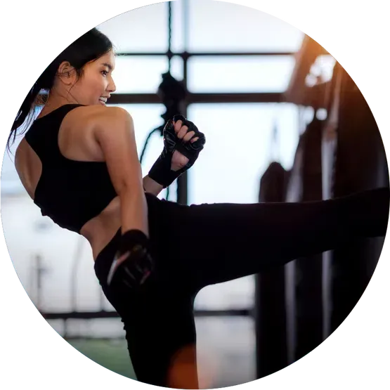 girl kicking a black back in a kickboxing studio