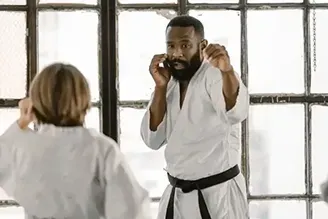 A man and a woman are practicing karate in a gym.