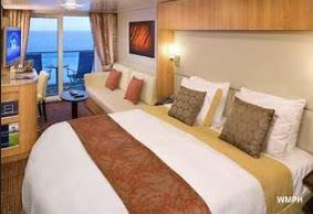 Cruise ship cabin, featuring a bed, seating area with ocean view, and television.