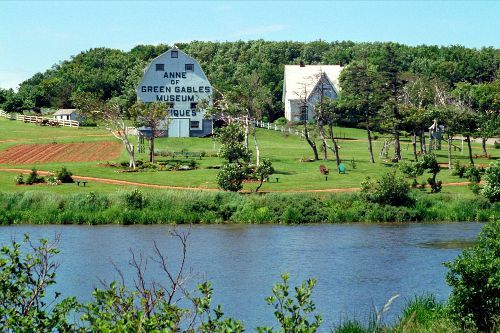 Green Gables Museum on Prince Edward Island, Canada, beside a calm lake. Blue and white buildings with green surroundings.