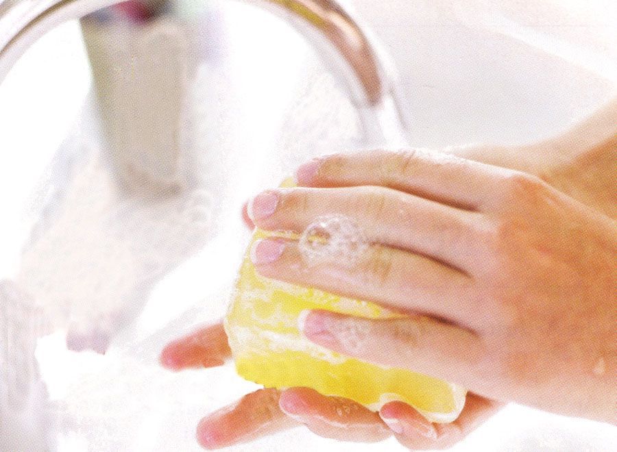 Person washing hands with yellow soap under running water.