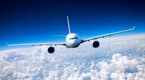 White passenger airplane flying above the clouds in a bright blue sky.
