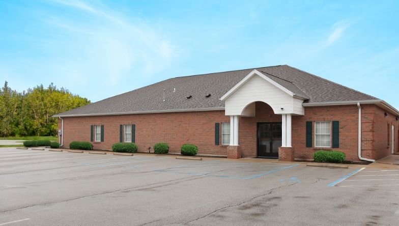 A large brick building with a parking lot in front of it.