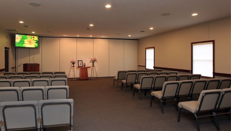 An empty funeral home with rows of chairs and a podium