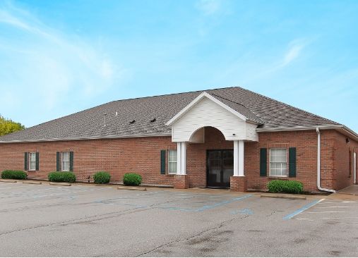 A large brick building with a parking lot in front of it.