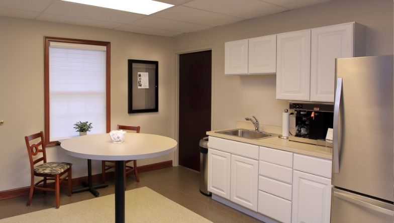 A kitchen with white cabinets and a stainless steel refrigerator