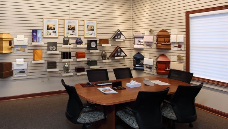 A conference room with a table and chairs in front of a wall with urns on it.