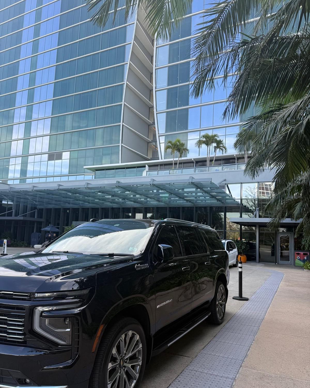A black suv is parked in front of a tall building.