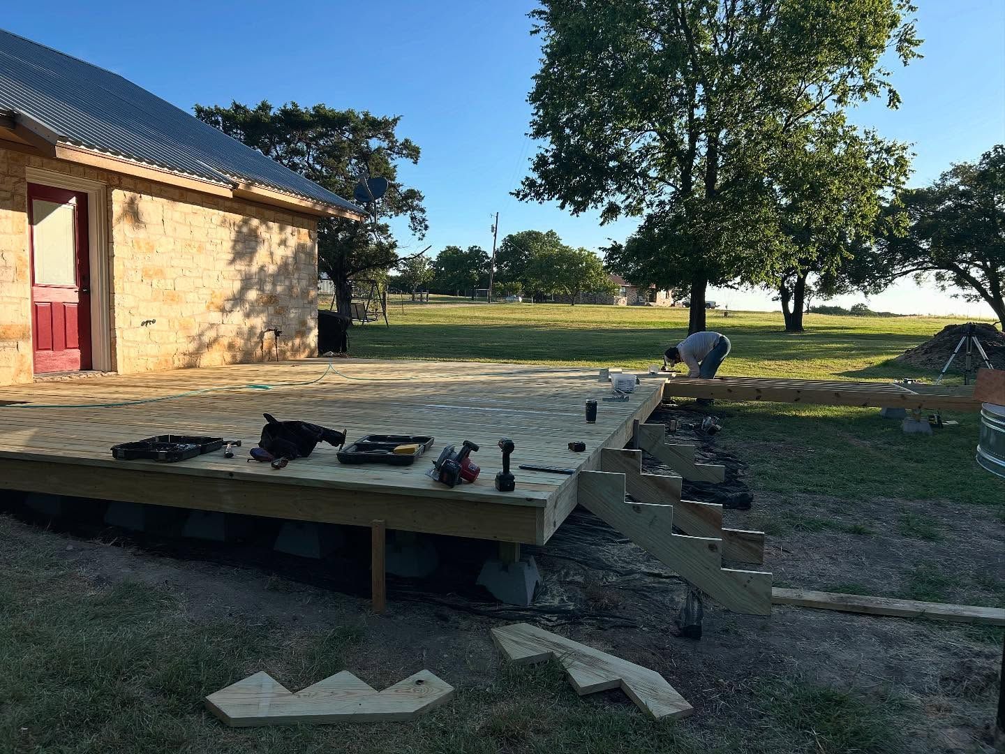 Deck construction in progress near a brick building; tools visible.