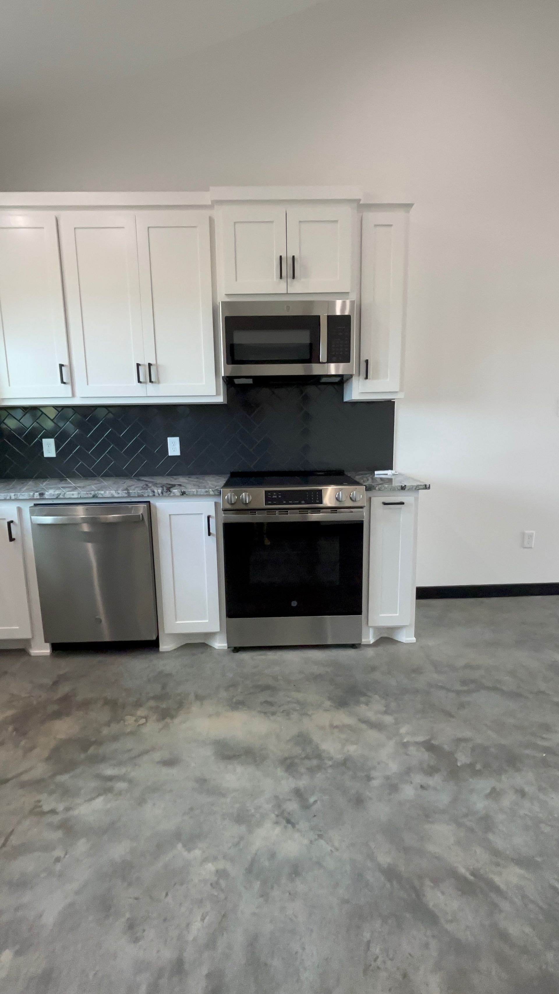 White kitchen cabinets, stainless steel appliances, and dark backsplash.