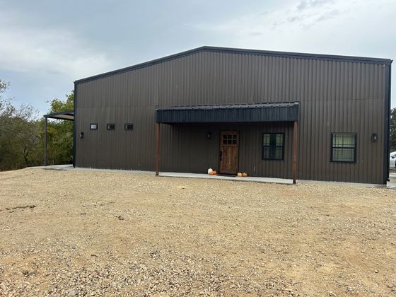 Brown metal building with a small porch and gravel yard.