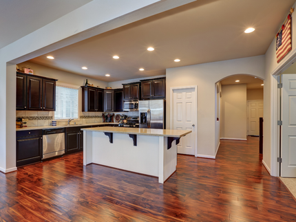Kitchen with dark cabinets, stainless steel appliances, and a white island on wood floors.