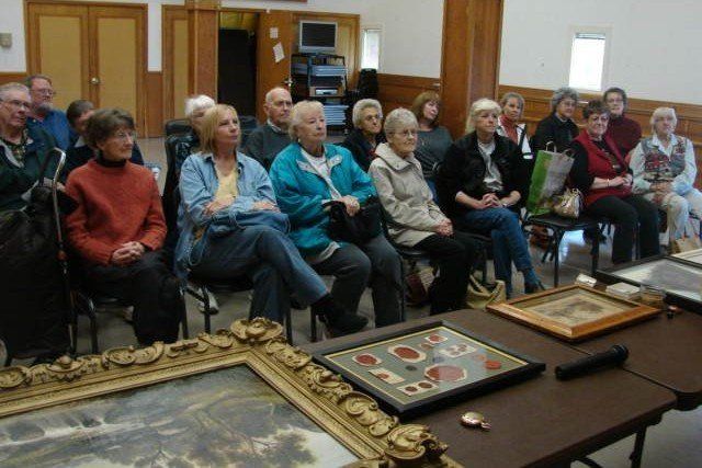 A group of people are sitting around a table with framed pictures on it