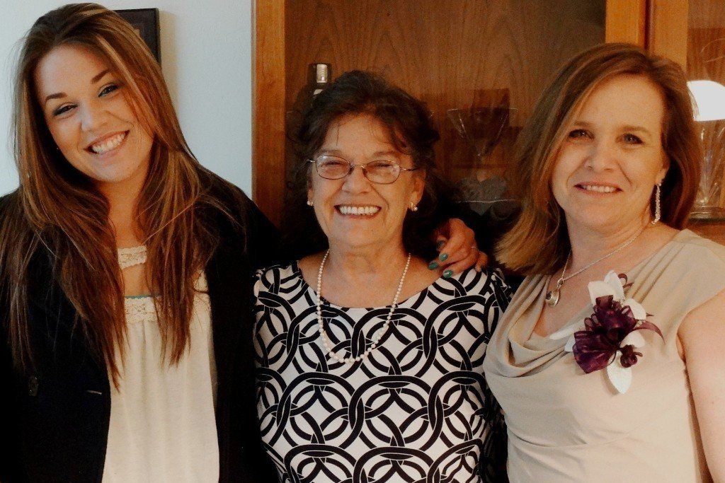 Three women are posing for a picture together and smiling for the camera.