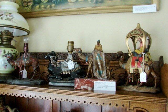 A shelf with statues of camels and a lamp on it